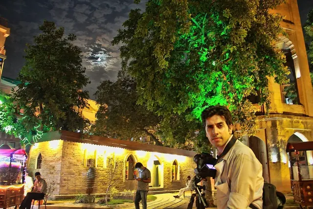 Naqqash Khan photographing at night in front of a lit heritage building